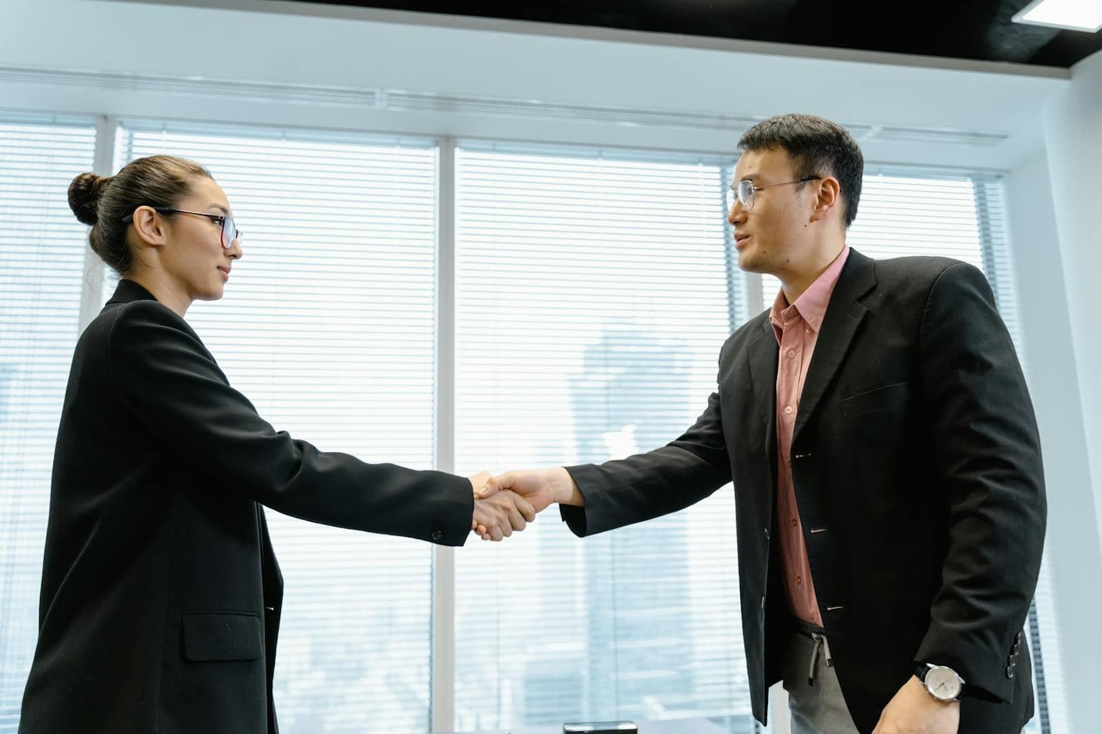 Two business professionals shaking hands in a modern office