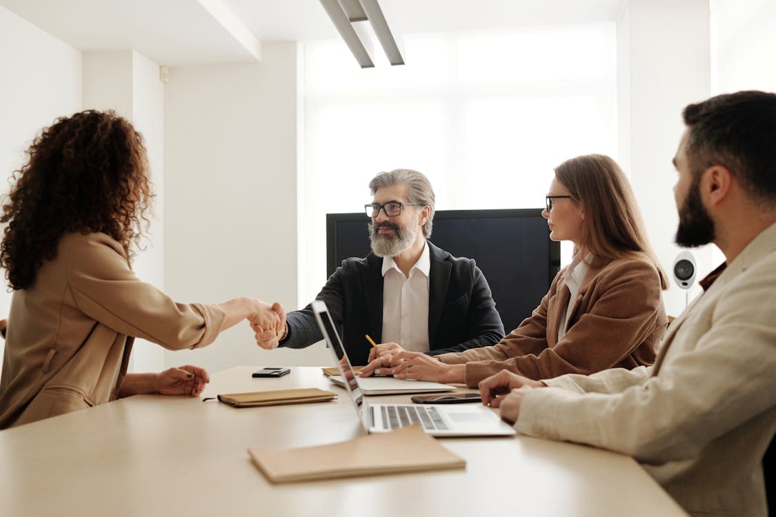 Business professionals shaking hands across a conference table in a formal office meeting