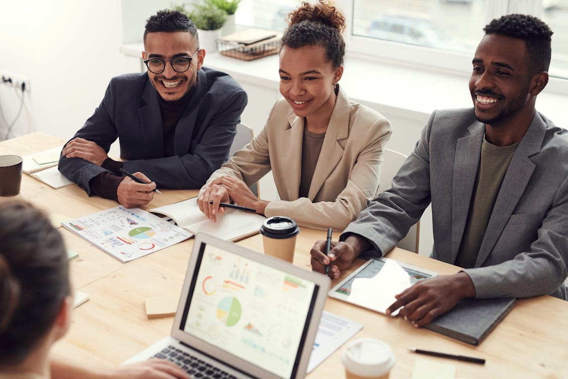 Diverse team of professionals in blazers collaborating around a conference table with charts and data